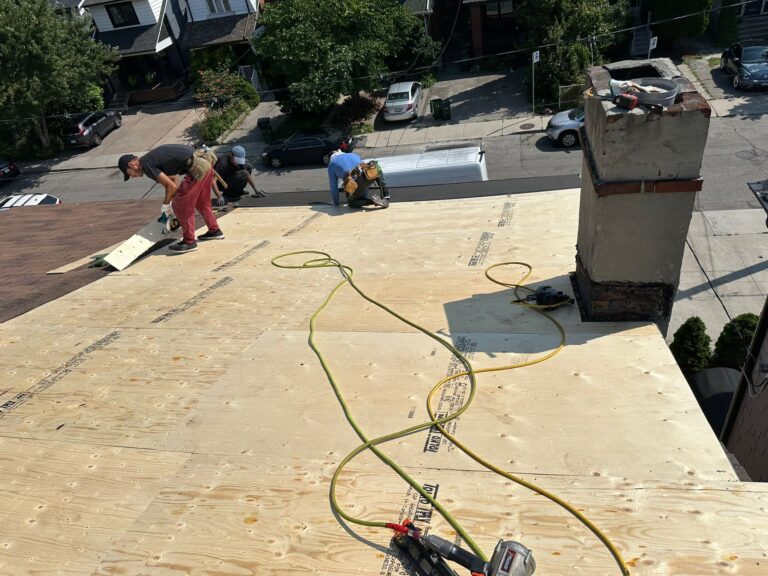 roof replacement project showing exposed plywood and crew working in Toronto