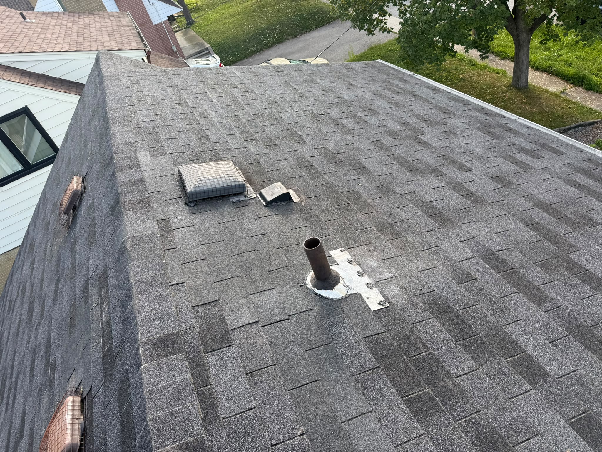Completed asphalt shingle roof repair with roof vents and ridge caps
